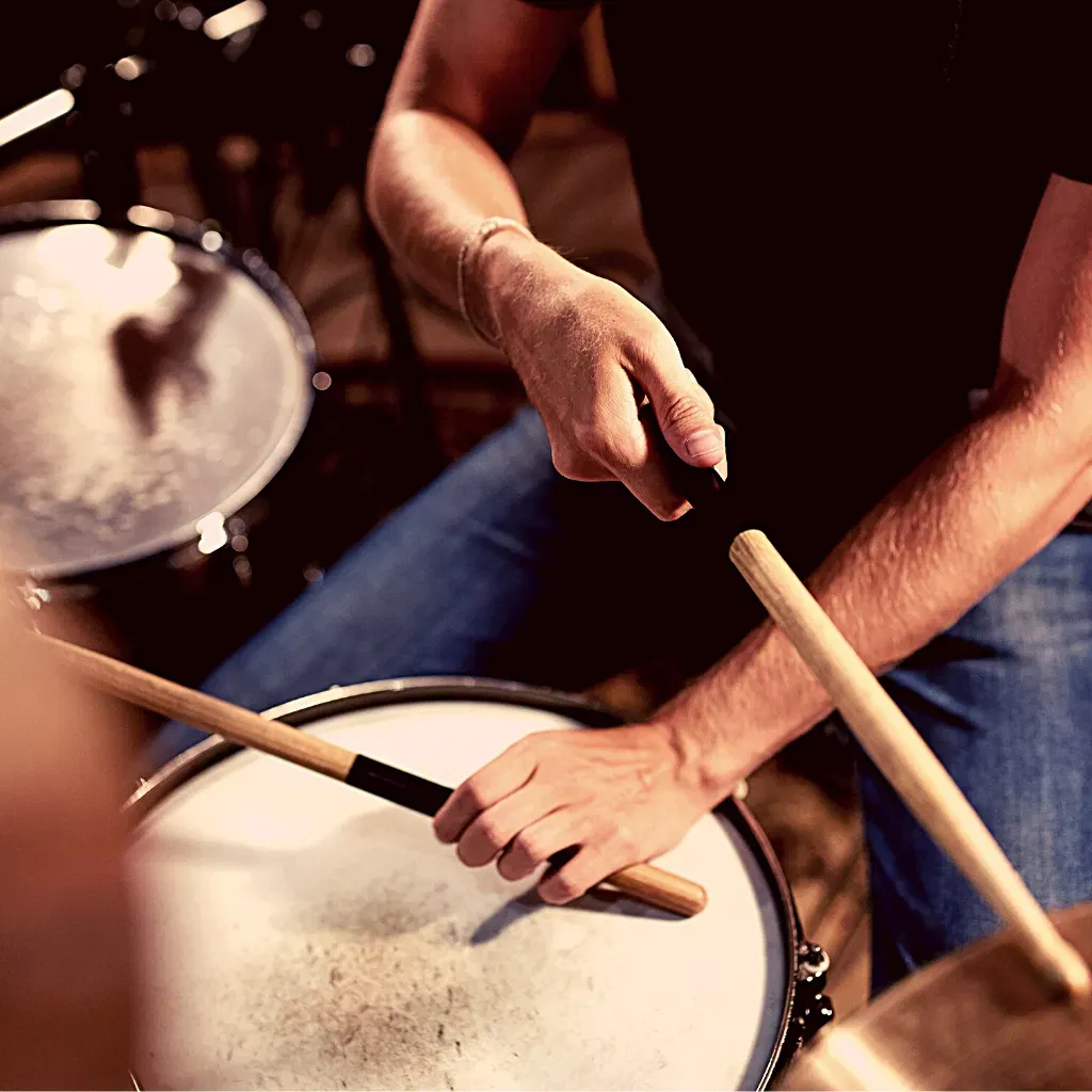 Drummer holding sticks over a snare drum