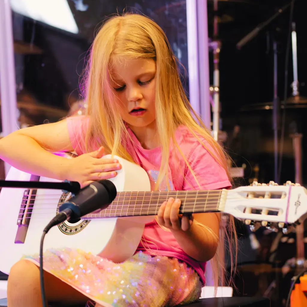 Young student practising guitar during a lesson