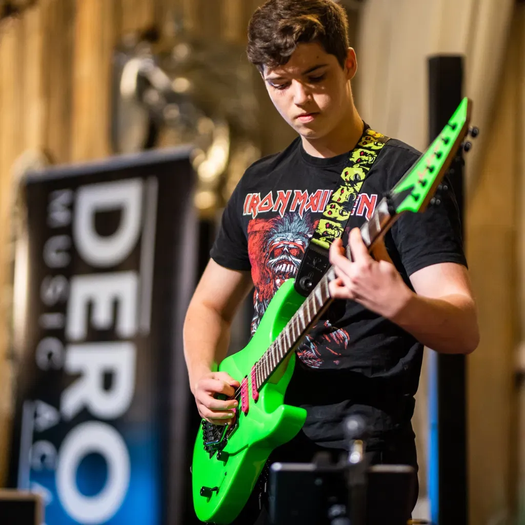 Student playing electric guitar at a DeRosa Music performance